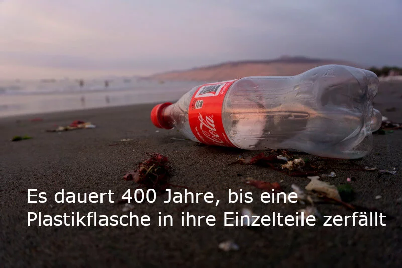Zero Waste: Bild einer leeren Coca-Cola-Flasche am Strand zur Verdeutlichung der Halbwertszeit von Plastik