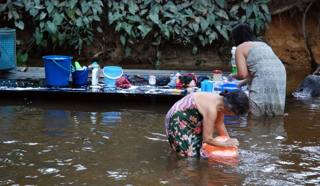 Frauen waschen ihre Wäsche in einem Fluss